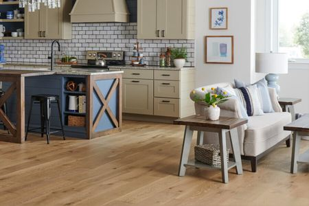 Warm wood flooring in an open-concept kitchen and living room with comfortable seating | Dalton Flooring of Georgia